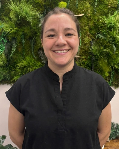 Robyn Morel, RN, smiling at the camera in professional black scrubs.