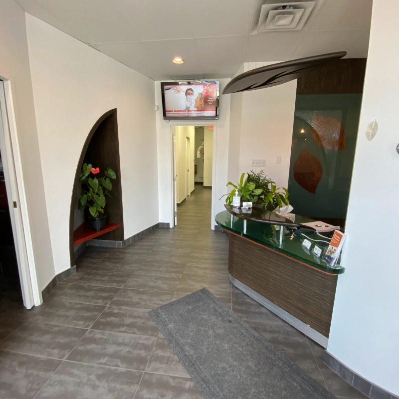 Modern dental office reception area with curved architectural features and green accent wall.