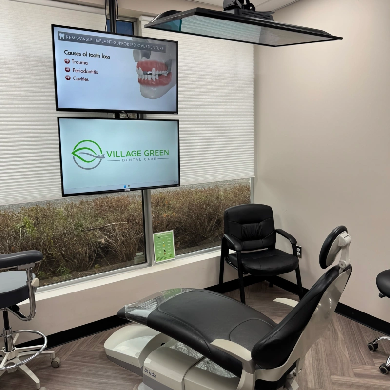Modern dental treatment room at Village Green Dental Care in Kanata with patient chair and educational displays.