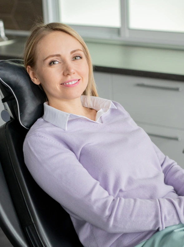 Woman in purple shirt smiling in dental office chair during periodontal consultation.