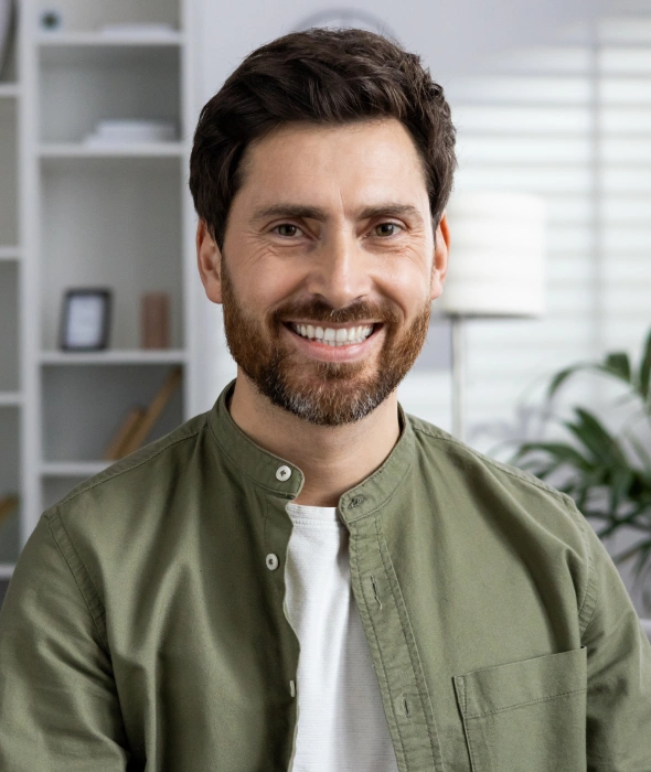 Smiling man in green shirt in modern dental office setting for restorative dentistry.