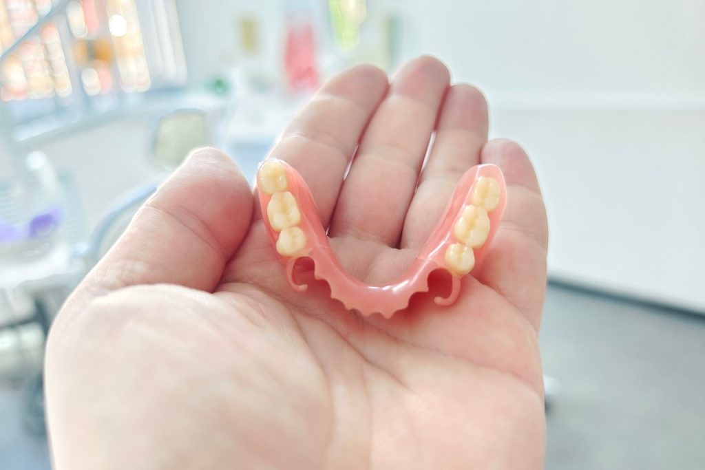 Denture patient holding their set of partial dentures