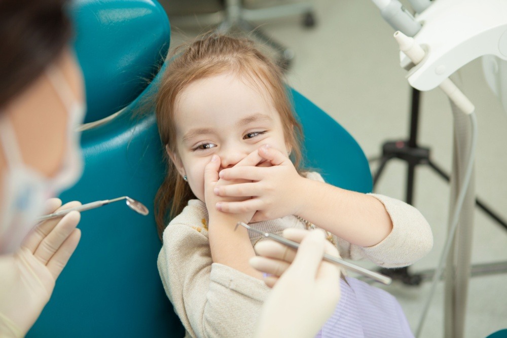 a young girl with dental anxiety refusing to let the dentist work